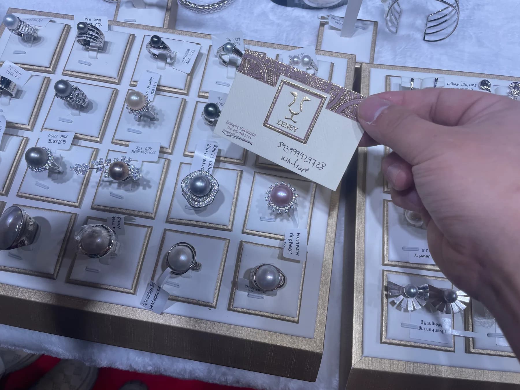 Buyer holding a Zalson Jewelry product card at the Las Vegas exhibition